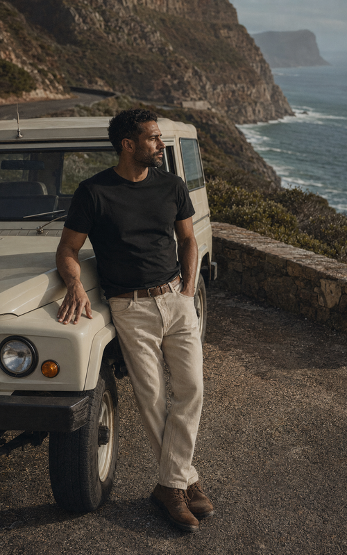 Man wearing a black tee beside a coastal road